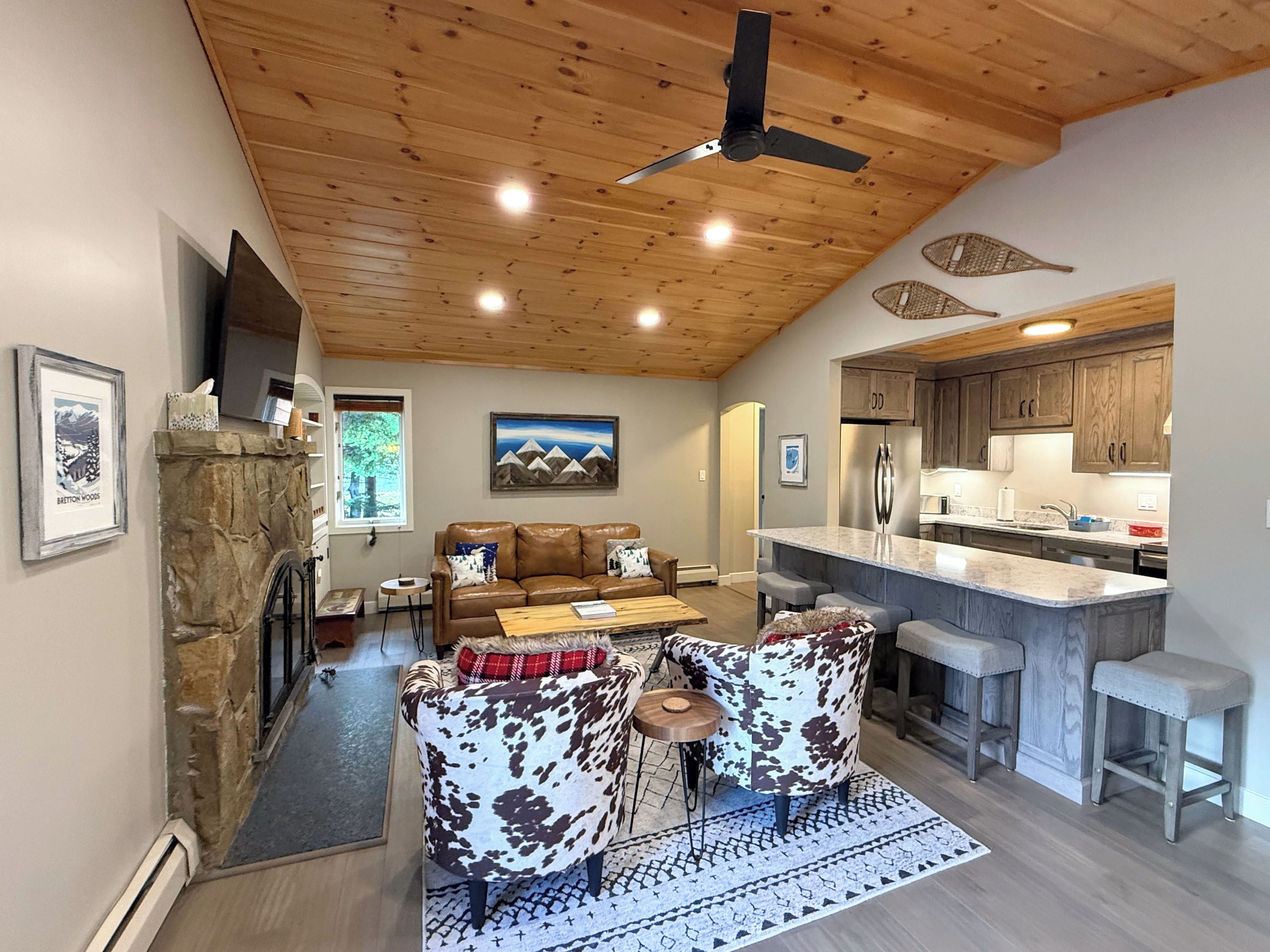 Una cocina moderna con una isla central, techo de madera y chimenea de piedra.