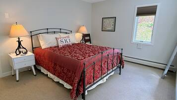 A bedroom with a bed, two bedside tables, lamps, a window, and a framed picture on the wall.
