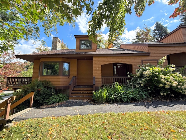 Une maison à deux étages, avec une façade en briques, un porche à l’avant et une pelouse bien entretenue.