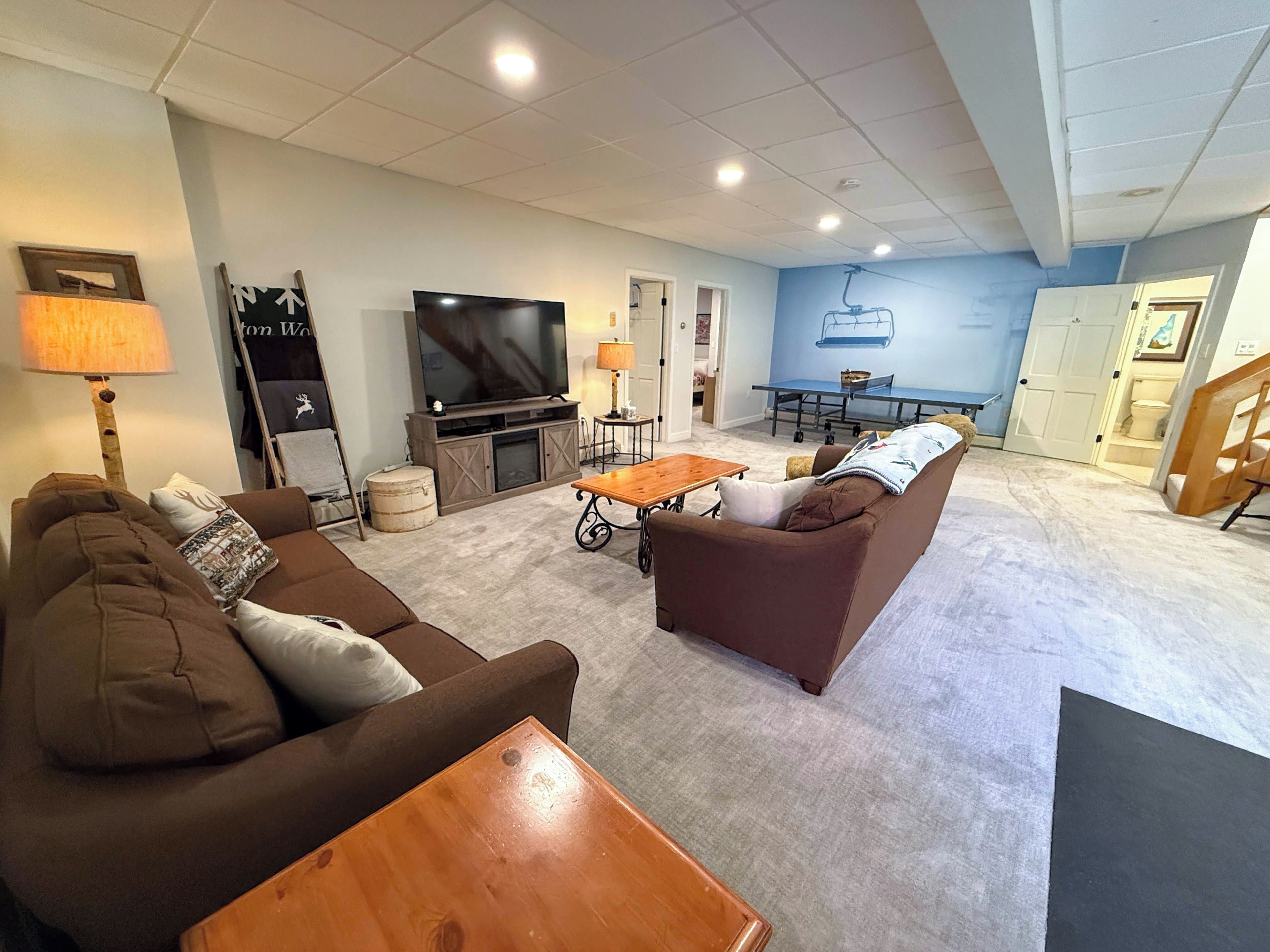 A living room with a sofa, a coffee table, a television, and a dining area with a table and chairs.