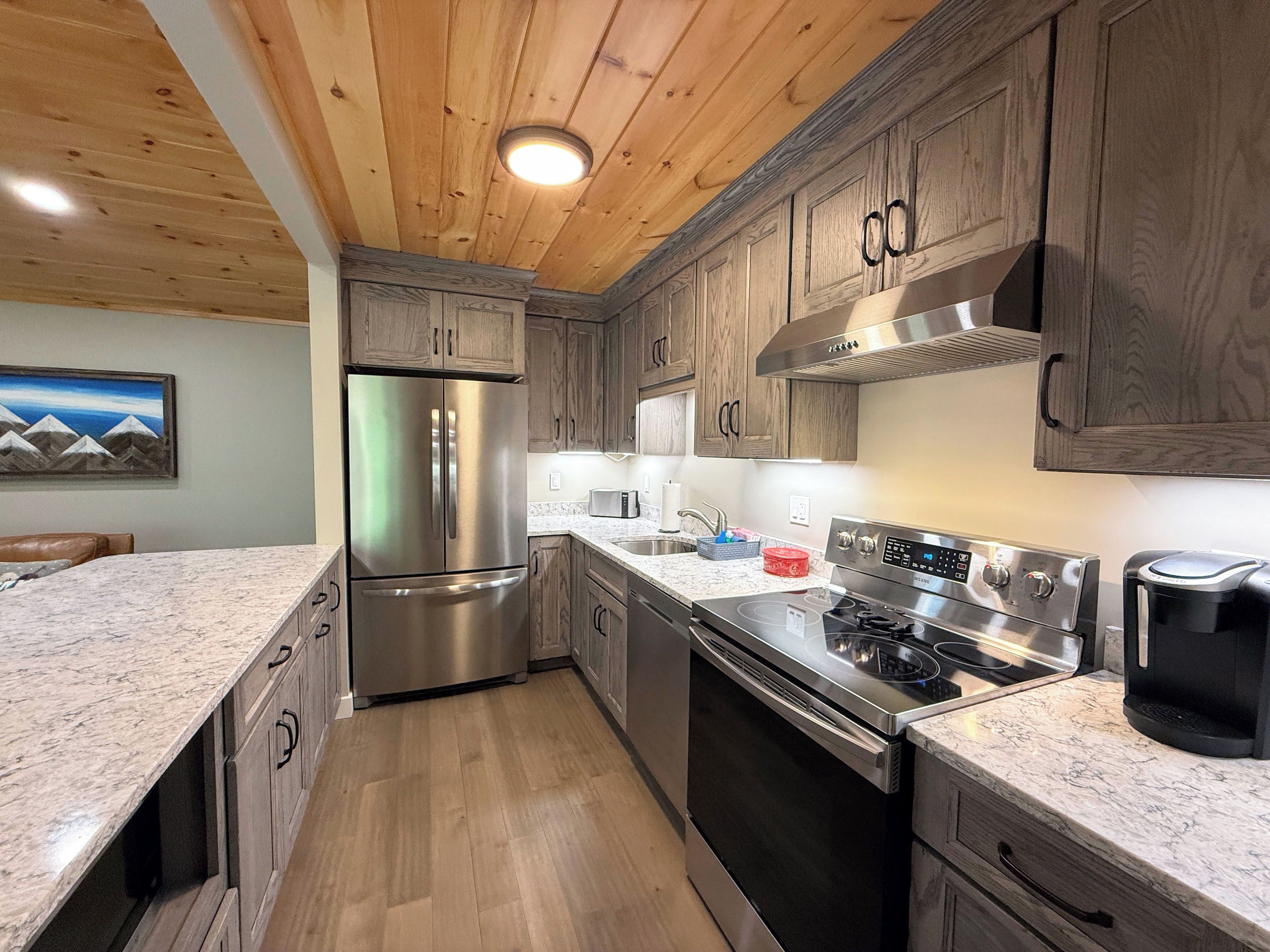 A modern kitchen with wooden cabinets, stainless steel appliances, and a granite countertop.
