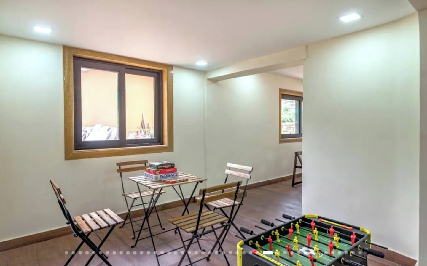 A room with a foosball table, a folding table with books, and two chairs.