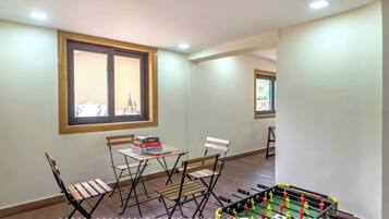 A room with a foosball table, a folding table with books, and two chairs.