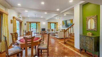 A spacious dining area with a high ceiling, a staircase, and a green accent wall.
