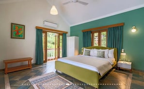 A bedroom with a bed, a nightstand, a bench, a window with curtains, and a ceiling fan. - Luxury Hillside Estate with Heated Indoor Pool (Lonavala)