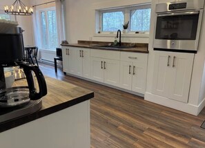 A modern kitchen with white cabinets, a stainless steel oven, and a black coffee machine.
