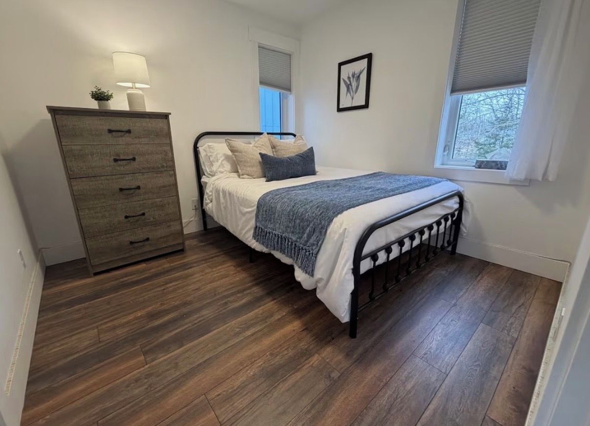 Une chambre à coucher avec un lit, une commode, une fenêtre et une porte.