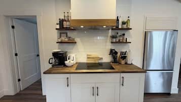 A modern kitchen with white cabinetry, a stainless steel refrigerator, and wooden countertops.