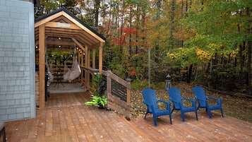 A wooden deck with a covered seating area, a table, and chairs.