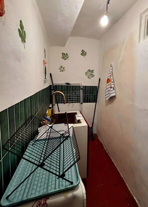 A narrow room with a metal rack, a white cabinet, and a broom leaning against the wall.