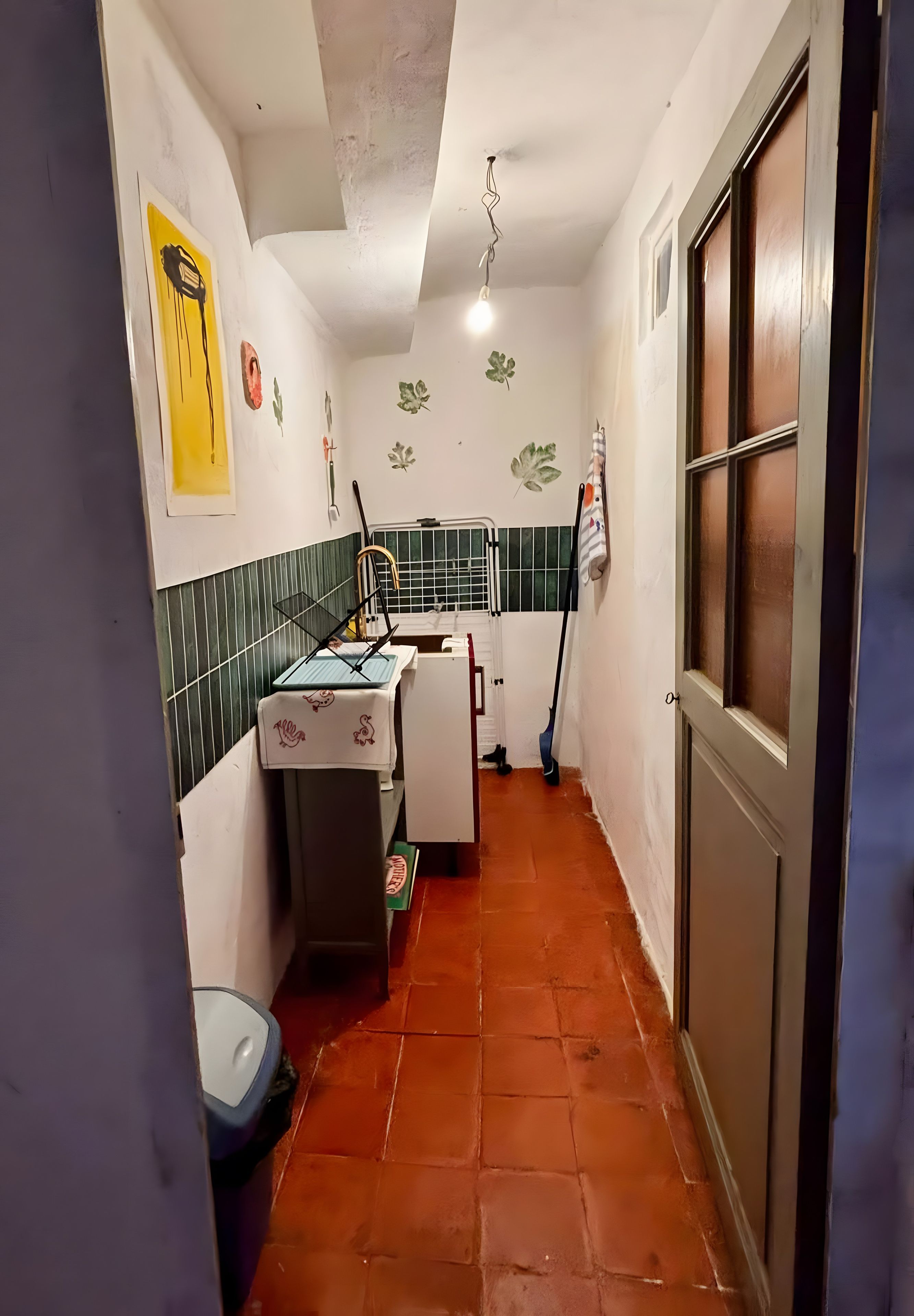 A narrow corridor with a tiled floor, a sink, and a window with a view.