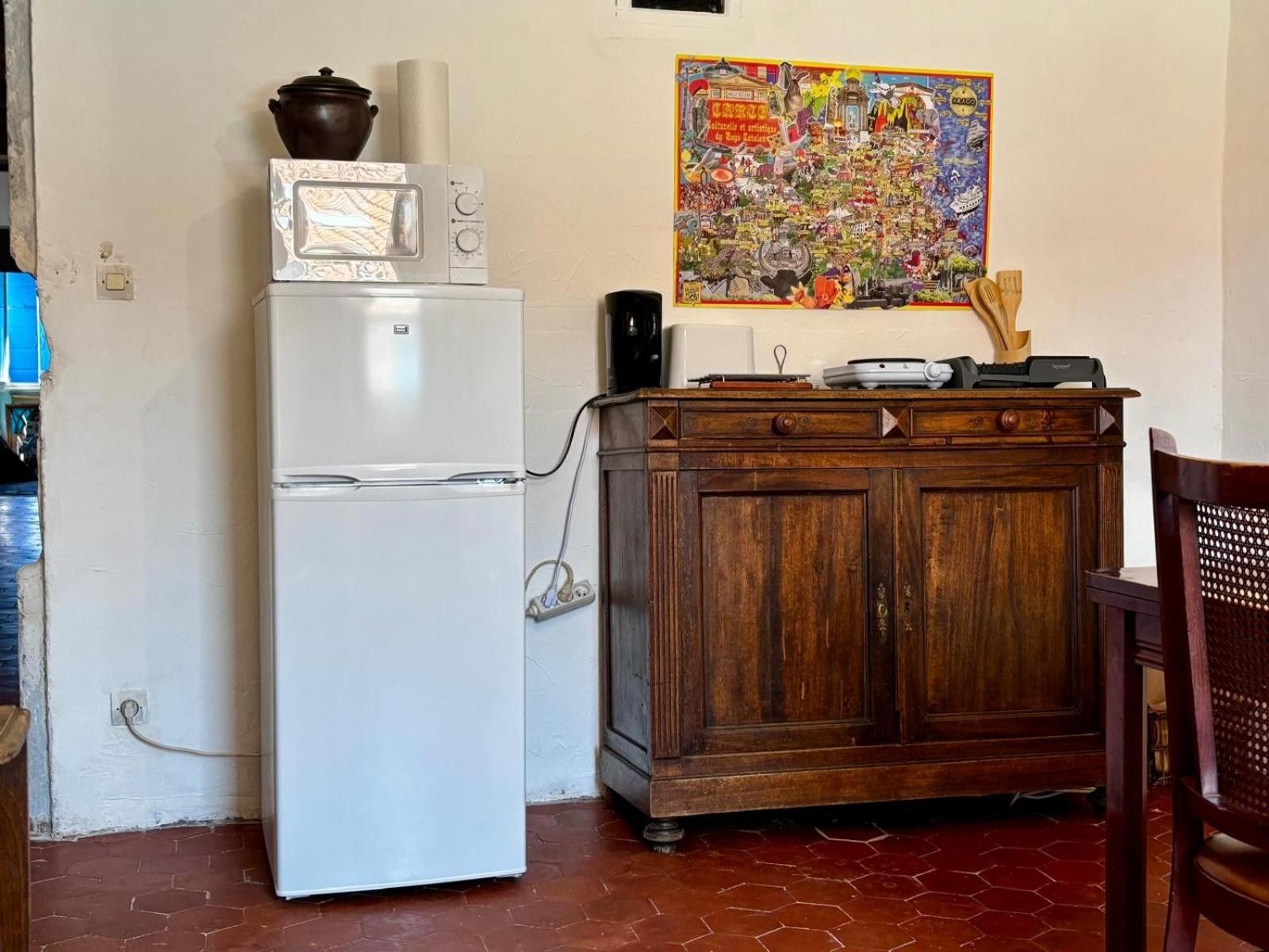 A kitchen with a white refrigerator, wooden cabinet, and a colorful poster on the wall.