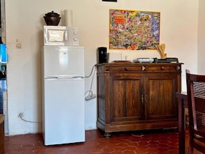 Una cucina con frigorifero bianco, mobiletto in legno e un poster colorato appeso al muro.