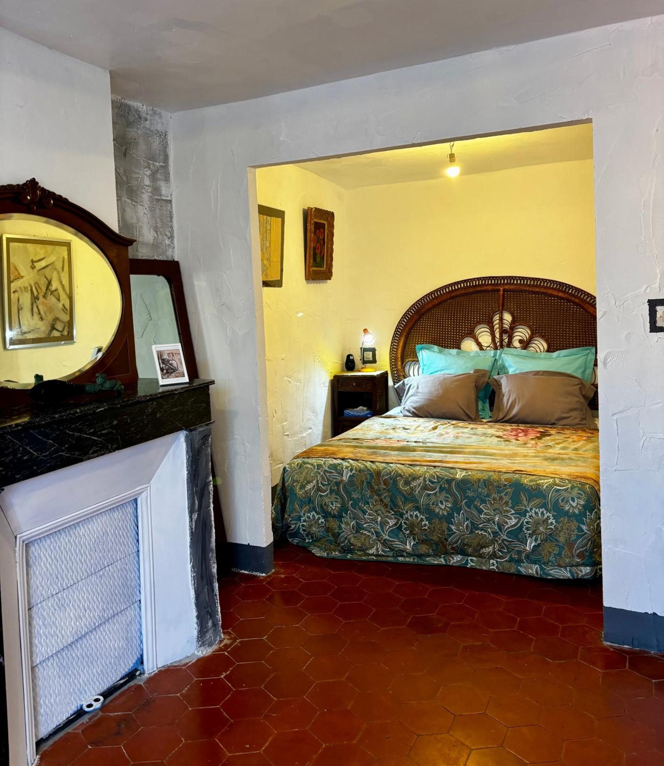 A bedroom with a bed, a nightstand, a dresser, and a mirror.