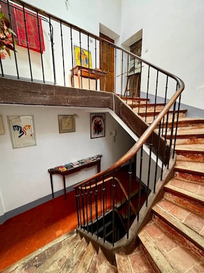 Una scala a chiocciola con ringhiera in legno e balaustre nere, che conduce a un piano superiore.