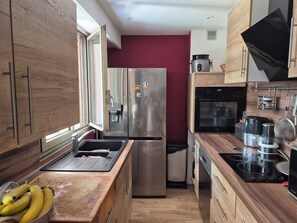 A compact kitchen with a stainless steel refrigerator, a built-in oven, and a stove. - Cozy 2-room apartment on the first floor in a quiet complex with a pool (Antibes)