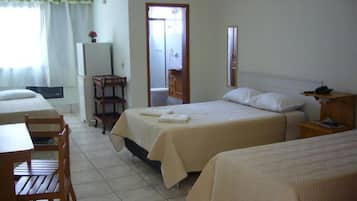 Quarto de hotel com duas camas, uma mesa pequena, uma cadeira, um refrigerador e banheiro visível por uma porta aberta.