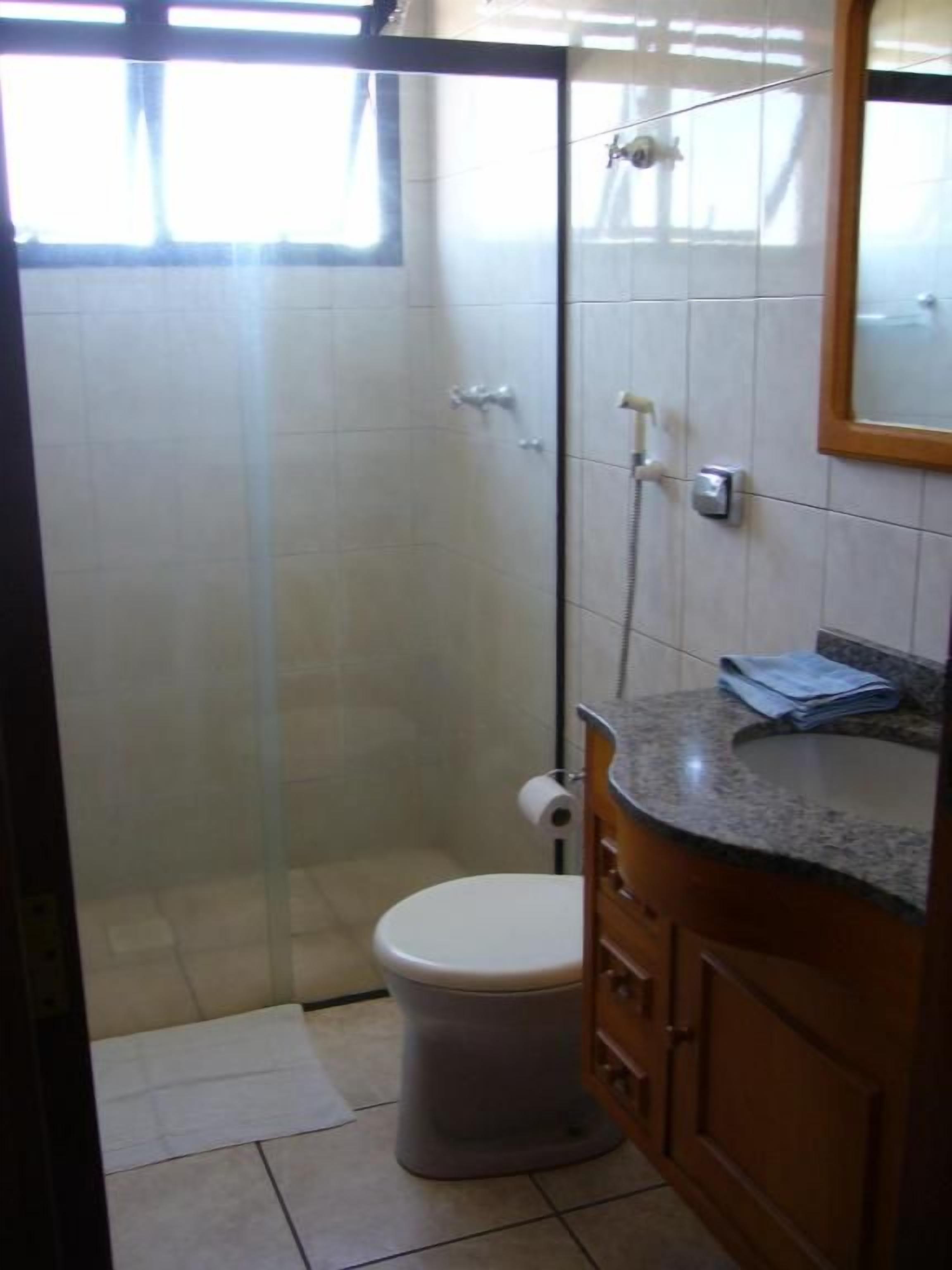 Un baño con cabina de ducha de vidrio, inodoro y tocador con espejo.