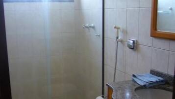 Un baño con cabina de ducha de vidrio, inodoro y tocador con espejo.