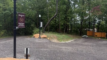Un camino de grava que conduce a una zona boscosa con un letrero de bienvenida al campamento y alojamiento Wild Ridge.