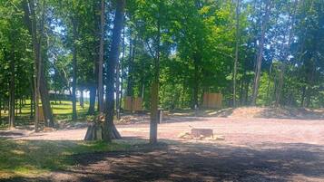 A forested area with a dirt path, trees, and a wooden structure.