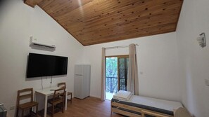 Una habitación con cama, escritorio con silla, televisor y ventana con cortinas.