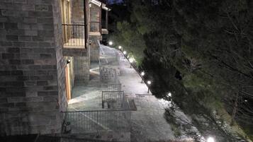 A stone building with a staircase leading to a balcony, surrounded by trees.