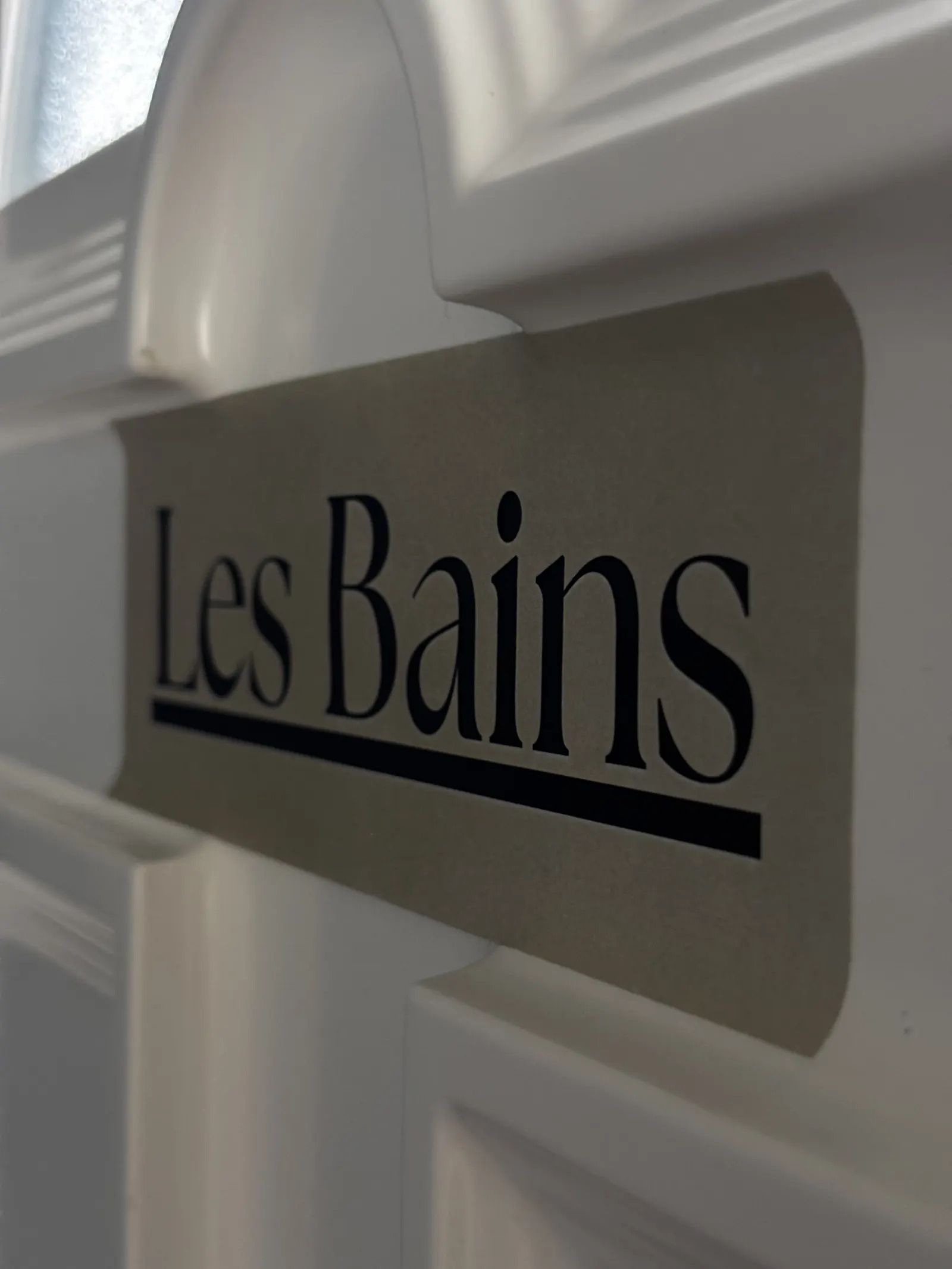 Un letrero con el texto 'Les Bains' sobre un fondo blanco.