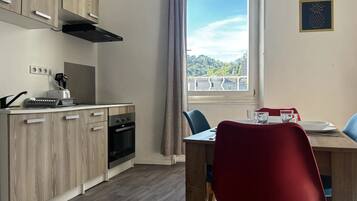 A modern kitchen with wooden cabinets, a built-in oven, and a window with a view of greenery.
