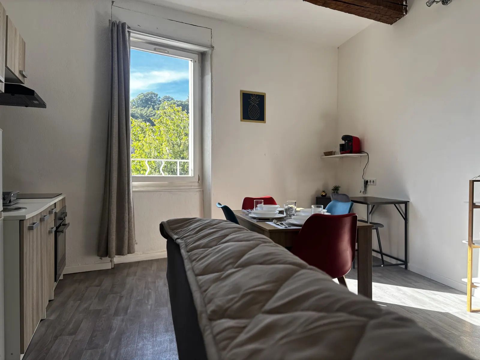 A room with a bed, a desk, and a window with a view of greenery.