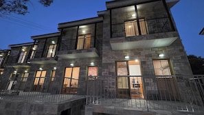 Un edificio de varios pisos con balcones, grandes ventanales y fachada de piedra.