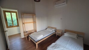 Une chambre avec un lit en bois, une fenêtre et un appareil de climatisation.