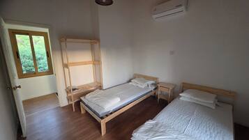 A room with a wooden bed, a window, and an air conditioning unit.