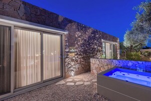 Un edificio moderno con paredes de piedra, puerta de cristal y una bañera de hidromasaje.