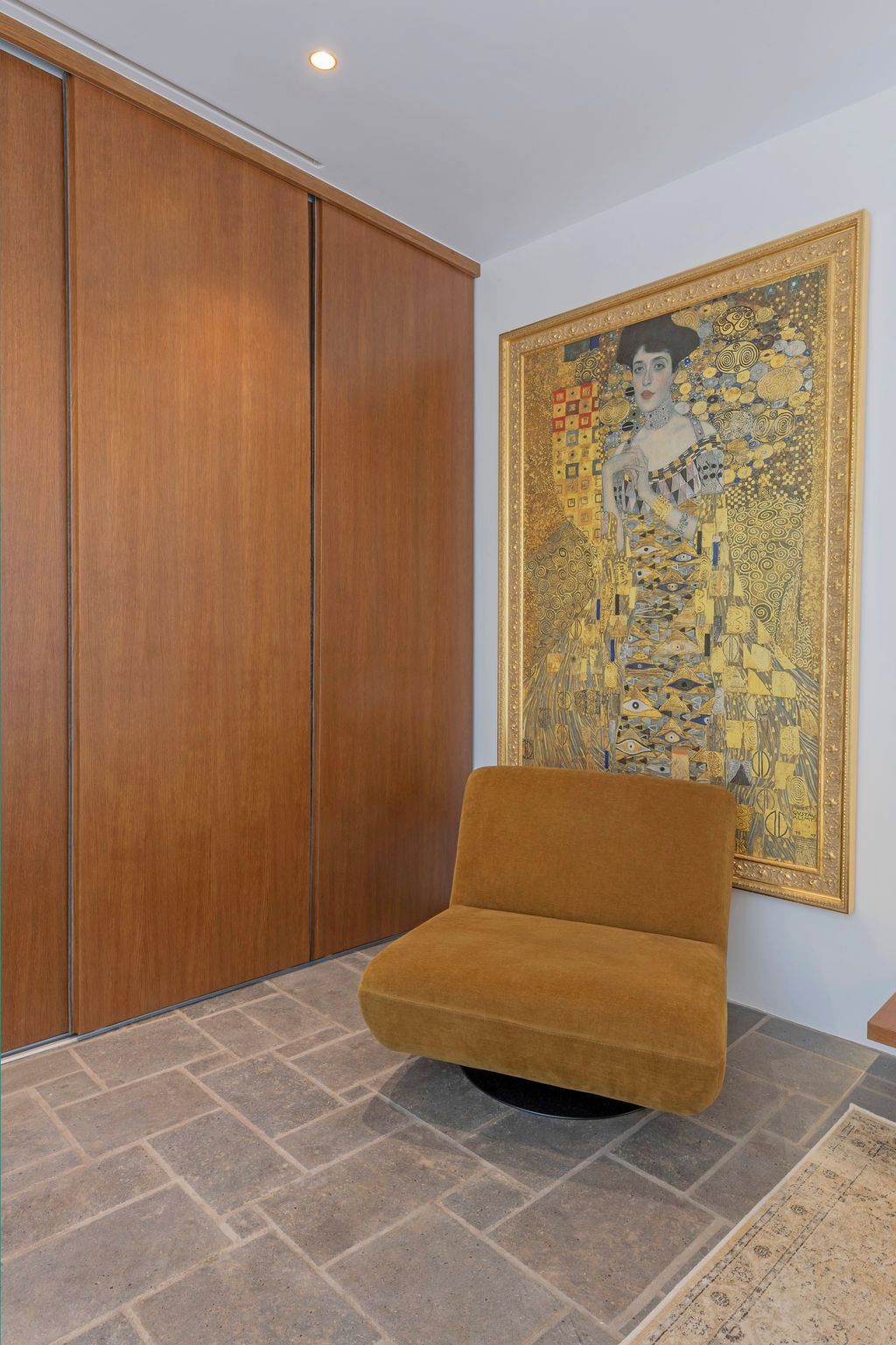 Ein Zimmer mit einem großen Holzschrank, einer Couch und einem großen gerahmten Kunstwerk an der Wand.