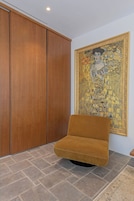Una stanza con un ampio guardaroba in legno, un divano e un quadro di grandi dimensioni appeso al muro.