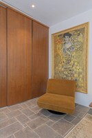 A room with a large wooden wardrobe, a sofa, and a large framed artwork on the wall.