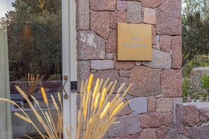 A stone wall with a plaque reading '203 Bungalow' and a door with a keypad lock.
