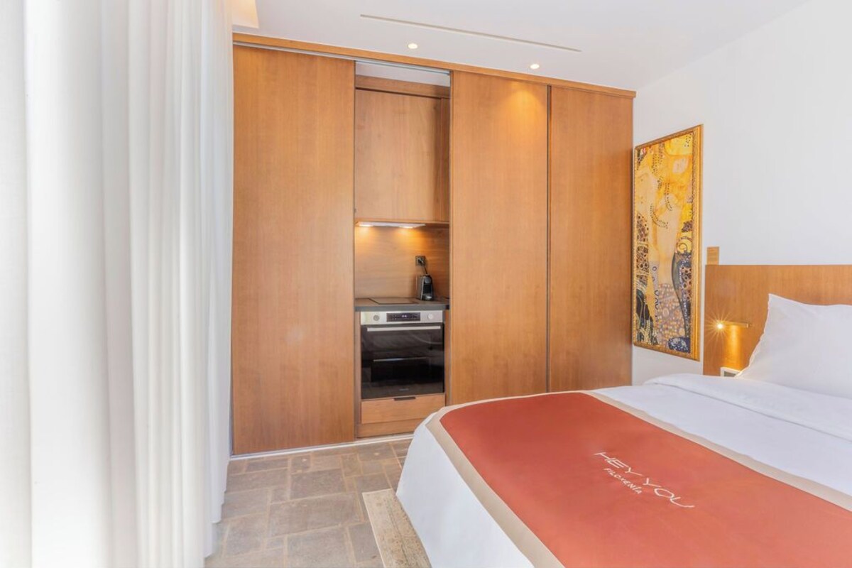 Ein Hotelzimmer mit einem Bett, einem Holzschrank, einer Küchenzeile und einem Bild an der Wand.