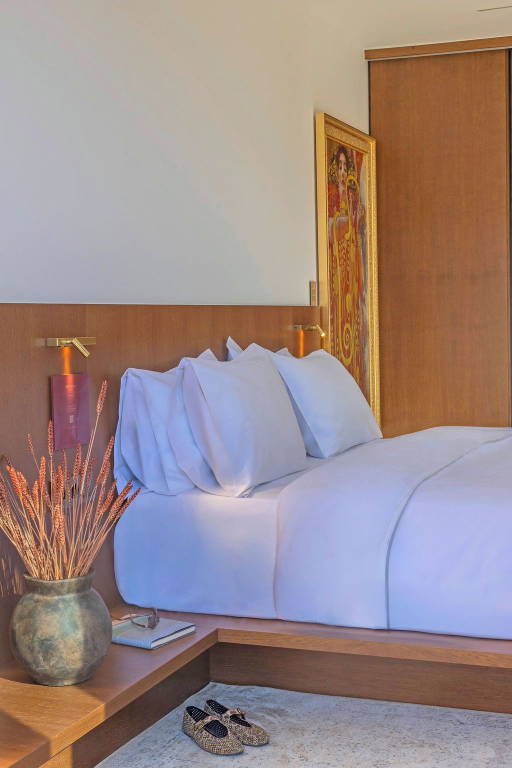 Ein Hotelzimmer mit Bett, Nachttisch und Wanddekoration.