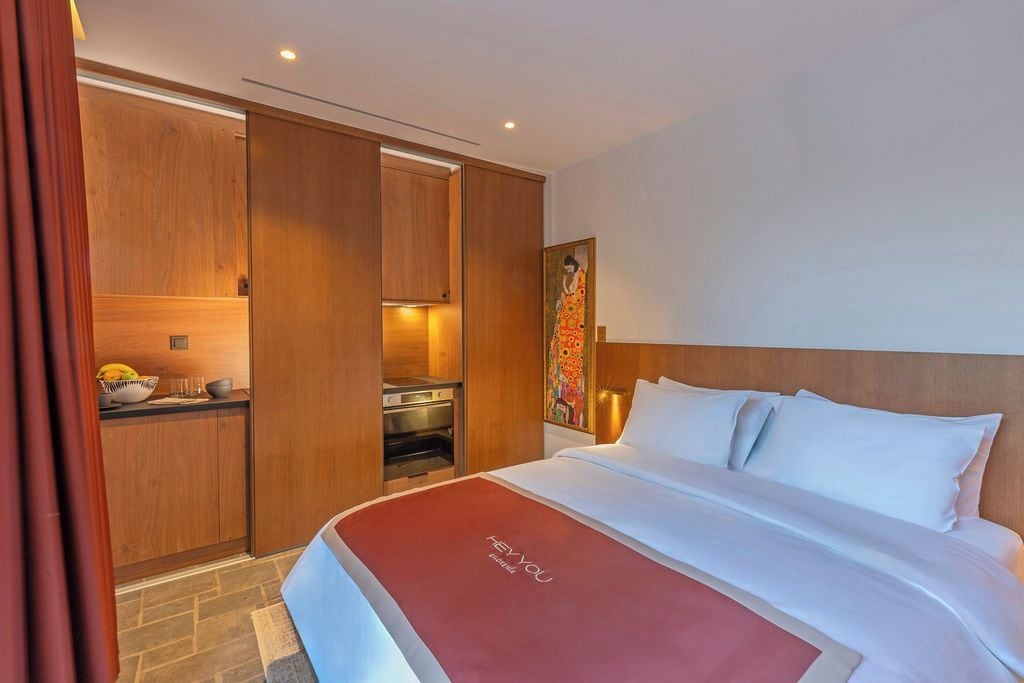 Ein Hotelzimmer mit Bett, einer Küchenzeile und einem Gemälde an der Wand.