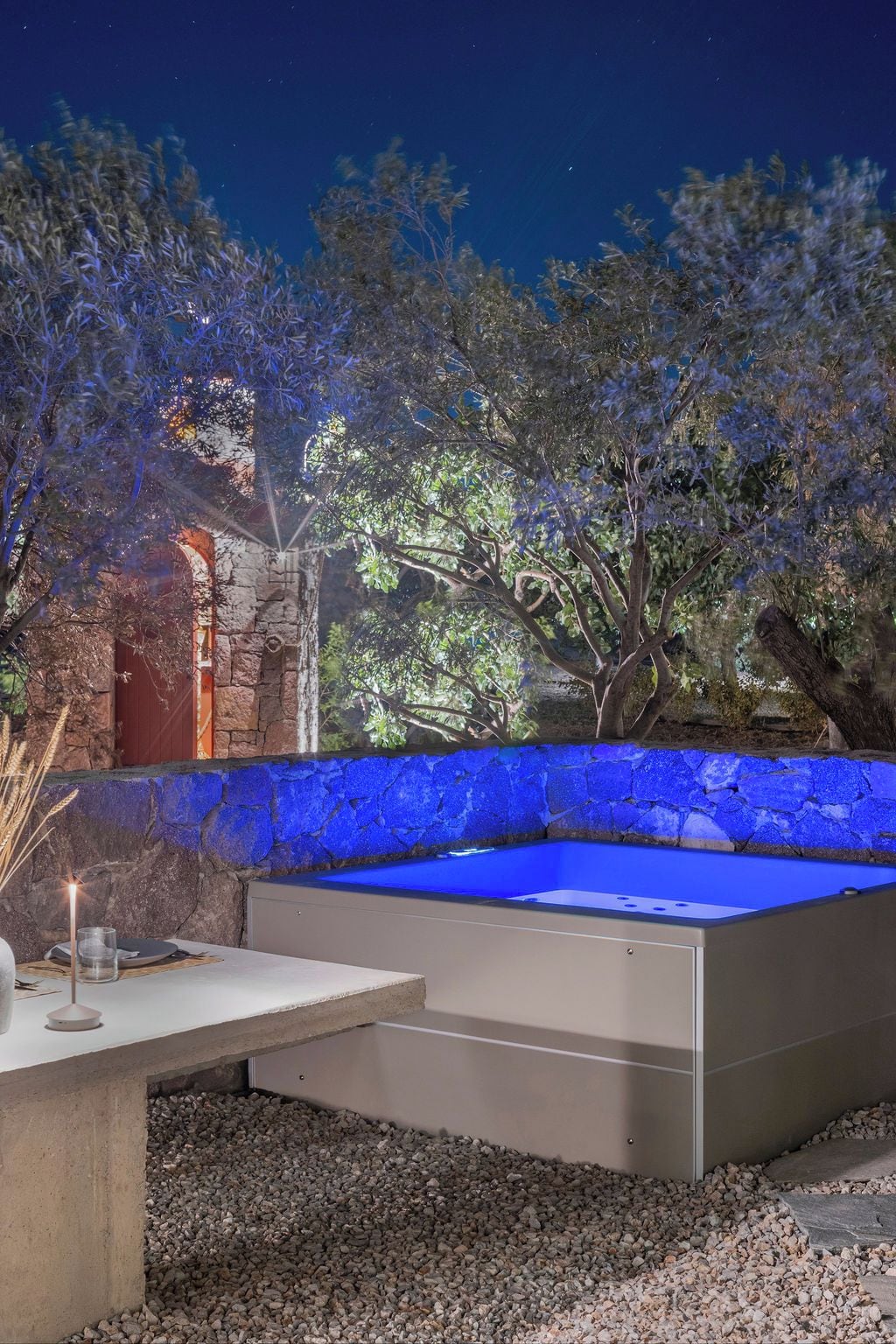 Un jacuzzi con pared de piedra y una mesa con una vela.
