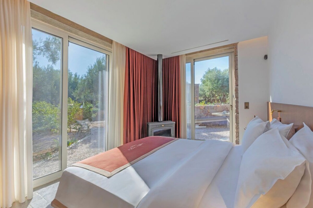 Ein Hotelzimmer mit Bett, einem kleinen Tisch und Blick ins Freie.