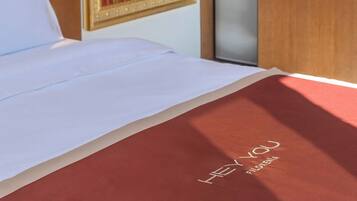Habitación de hotel con una cama, un cuadro, un armario y un pequeño mueble.