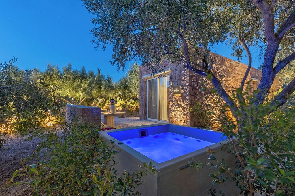 A spa area with a hot tub surrounded by stone walls and trees.