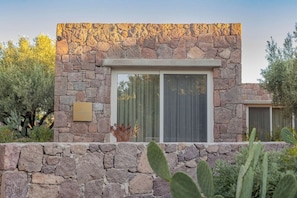 A stone building with a large window and a plaque. - Hey You Filoxenia (Egina)