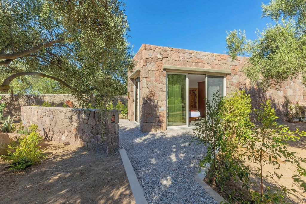A stone building with a gravel pathway leading to a glass door entrance.