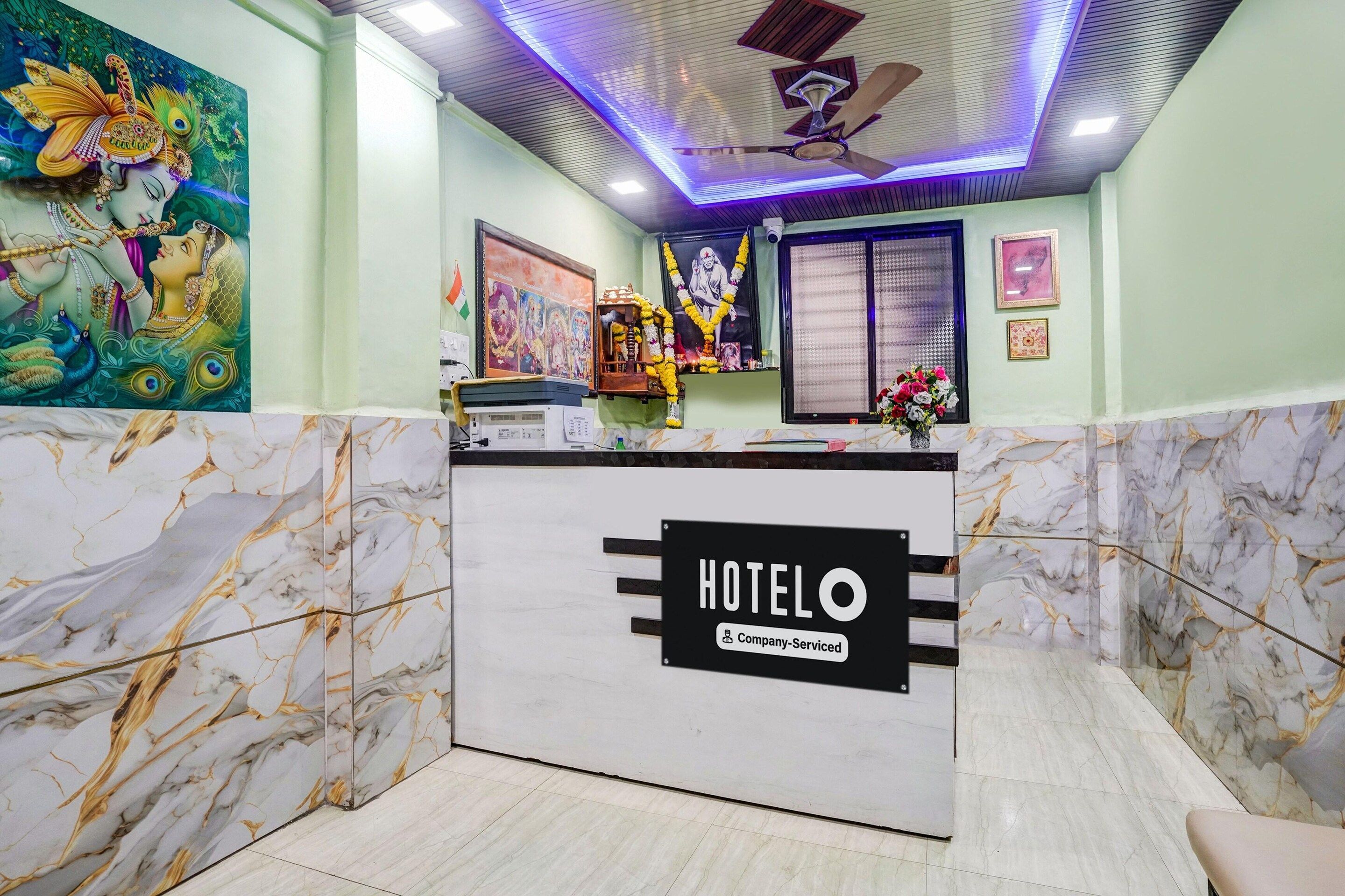 Una recepción de hotel con diseño de mármol, un ventilador de techo y una pared decorada con arte religioso.