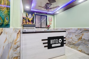 Ein Hotelrezeptionsschalter mit Marmordesign, einem Deckenventilator und einem Schild, das angibt, dass es sich um ein betriebliches Hotel handelt.