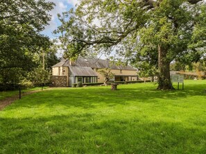 A building with a stone facade, a grassy lawn, and a large tree in the foreground. - The Apple Store at Gileston Manor (Barry)